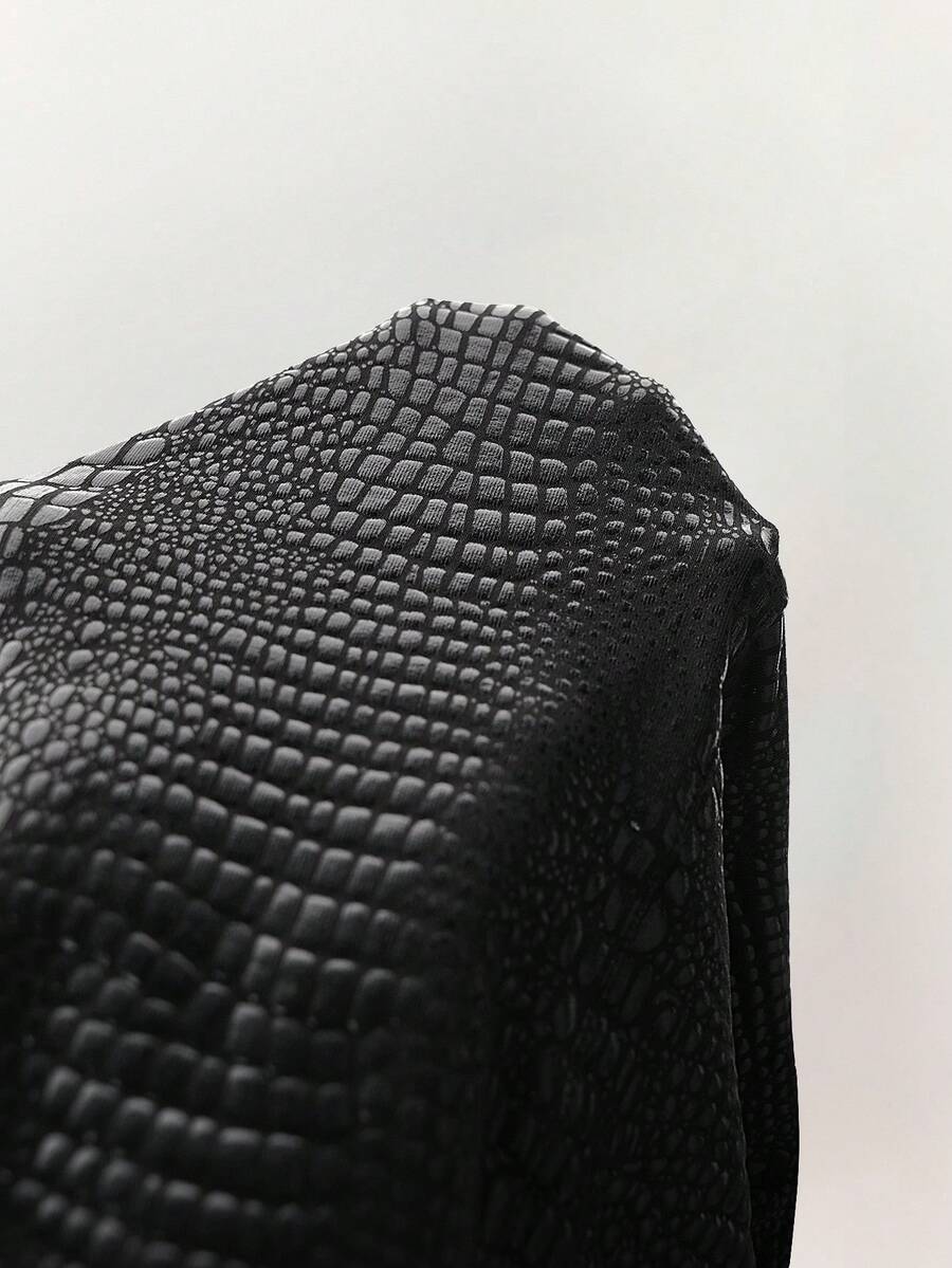 Macro view of black embossed crocodile texture on dress fabric
