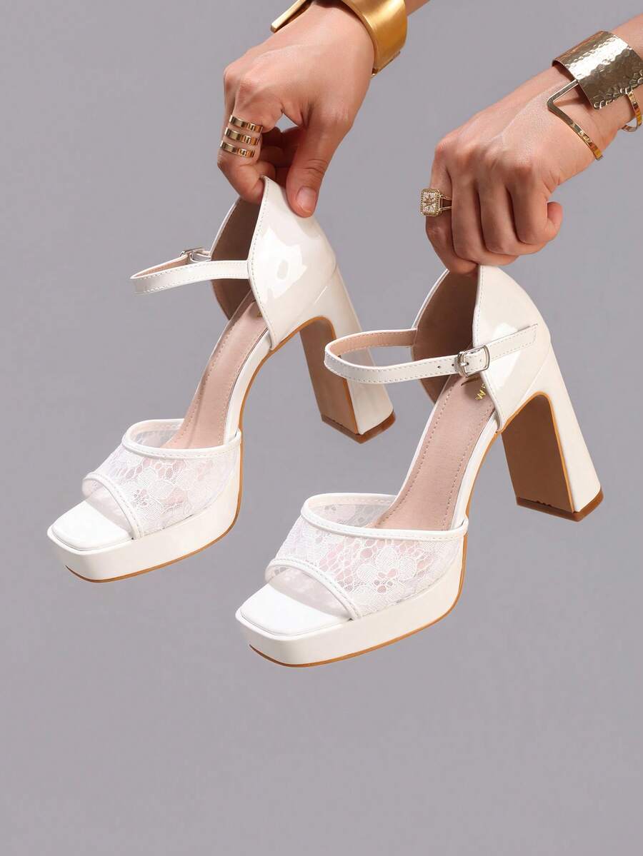 White platform sandals held by hands showing square open toes and chunky heels