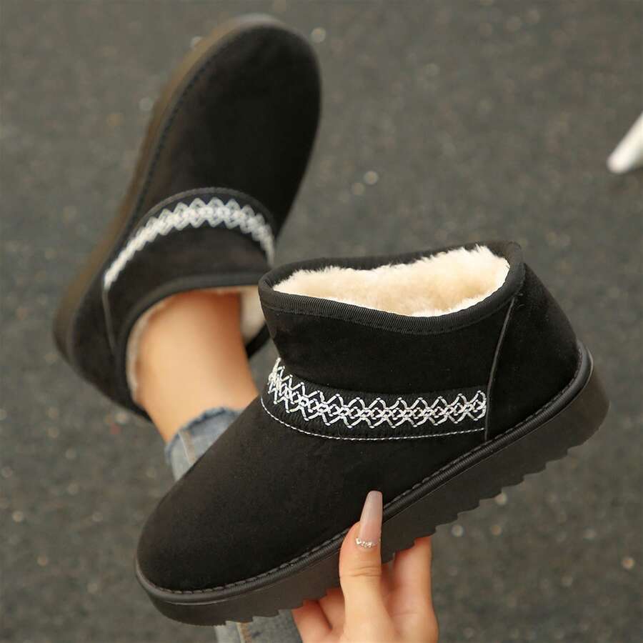 Front three-quarter view of black fuzzy ankle boots with white embroidery