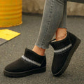 Side view of black suedette ankle boots worn with jeans outdoors