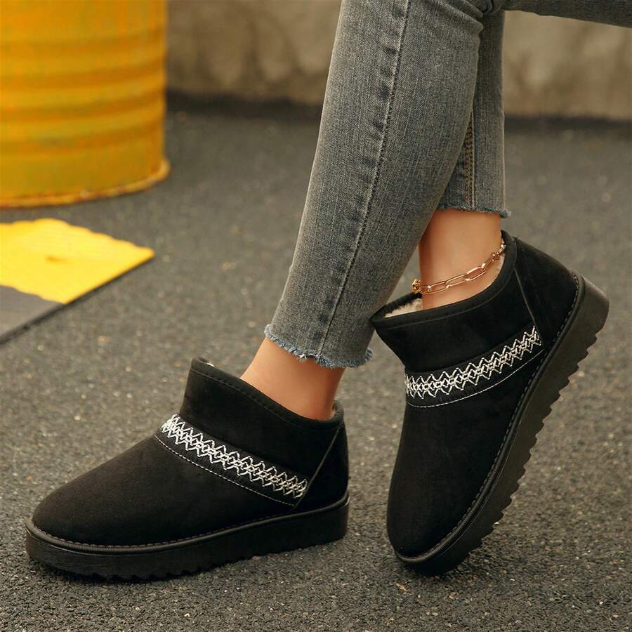Side view of black suedette ankle boots worn with jeans outdoors