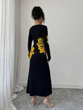 Back full view of black and mustard floral slim-fit knit midi dress with subtly flared hem