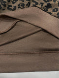 Close-up of leopard-print hoodie interior seam, fine knit lining, and wide brown rib-knit hem