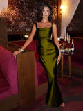 Front three-quarter view of olive green ruched satin evening gown in ornate setting