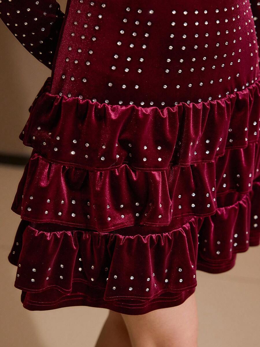 Close-up of burgundy velvet mini dress showing sparkling rhinestones and gathered skirt tiers