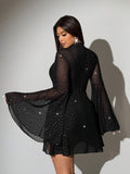 Front selfie view of black sheer embellished mini dress with long flared sleeves and camisole layer