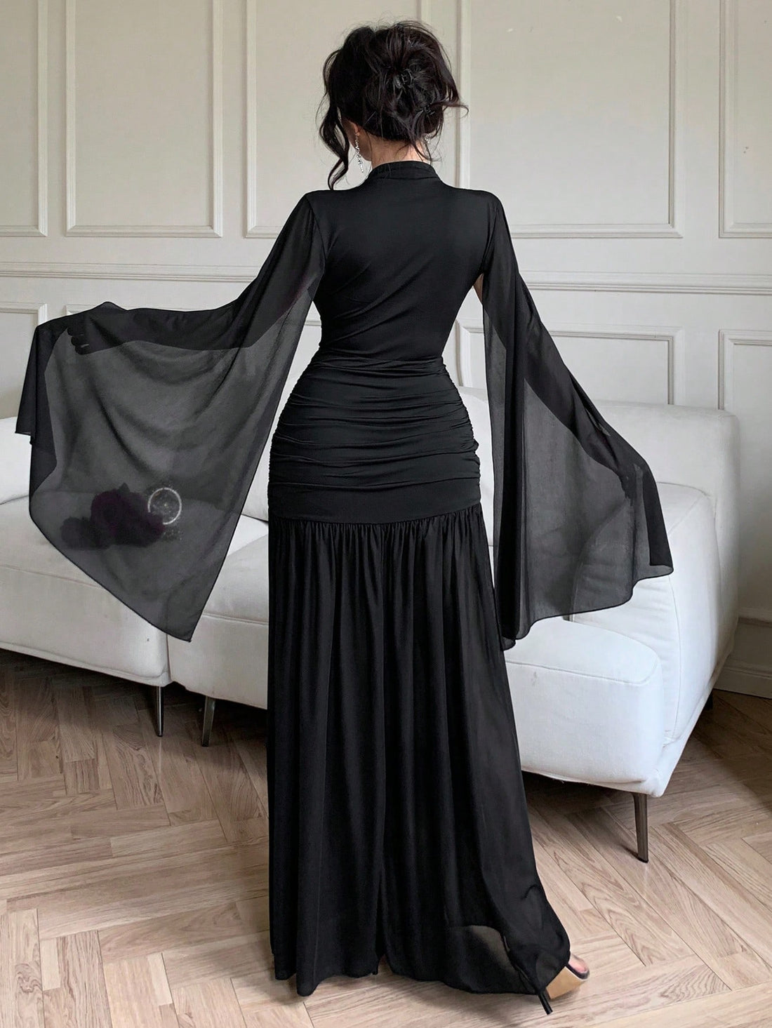 Make a statement at your next formal affair in this stunning black maxi dress. The ruched waist creates a flattering silhouette while dramatic flared sleeves add an unexpected touch of flair and movement. Perfect for galas, weddings, or any occasion calling for sophisticated elegance with a hint of playful drama. The timeless black hue pairs effortlessly with your favorite accessories, letting you shine in understated luxury.