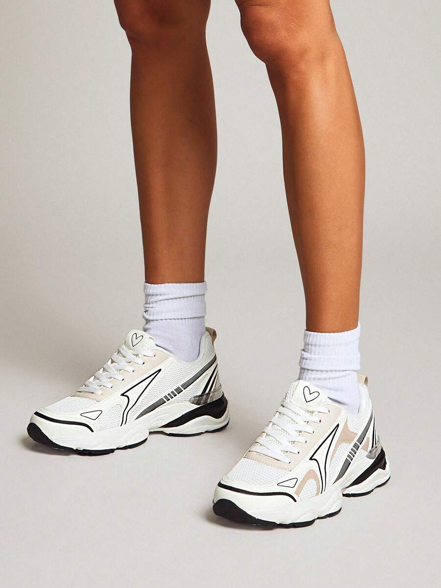 On-foot front three-quarter view of white lace-up mesh trainers with black accents
