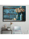 Desk corner view of white flower wall art with blue jars and distressed wood
