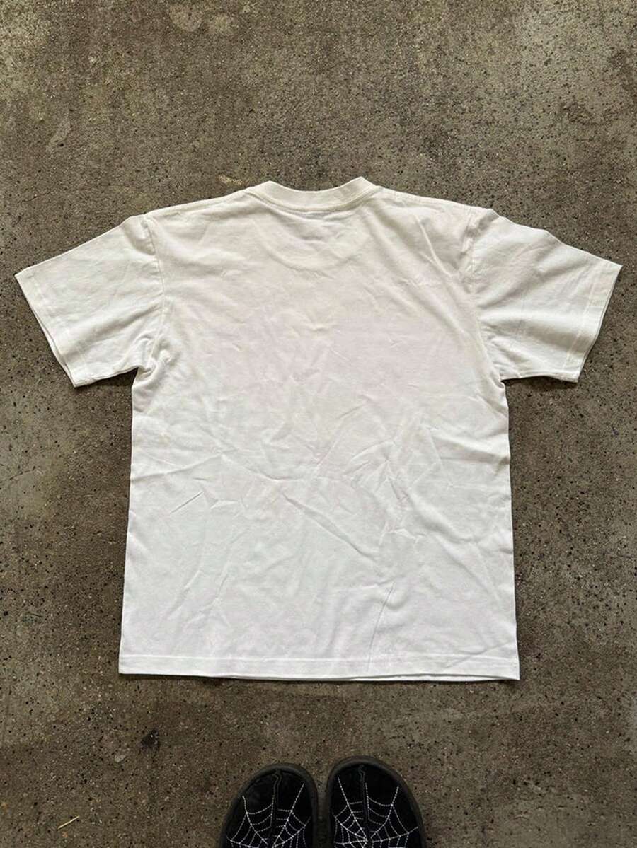 Front flat lay of white crew-neck T-shirt with distressed 2000s internet graphic and denim styling