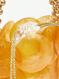 Close view of orange shell-disc mini bag with gold hardware