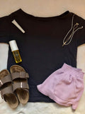 Back flat-lay of plain dark loose short-sleeve T-shirt styled with lilac shorts