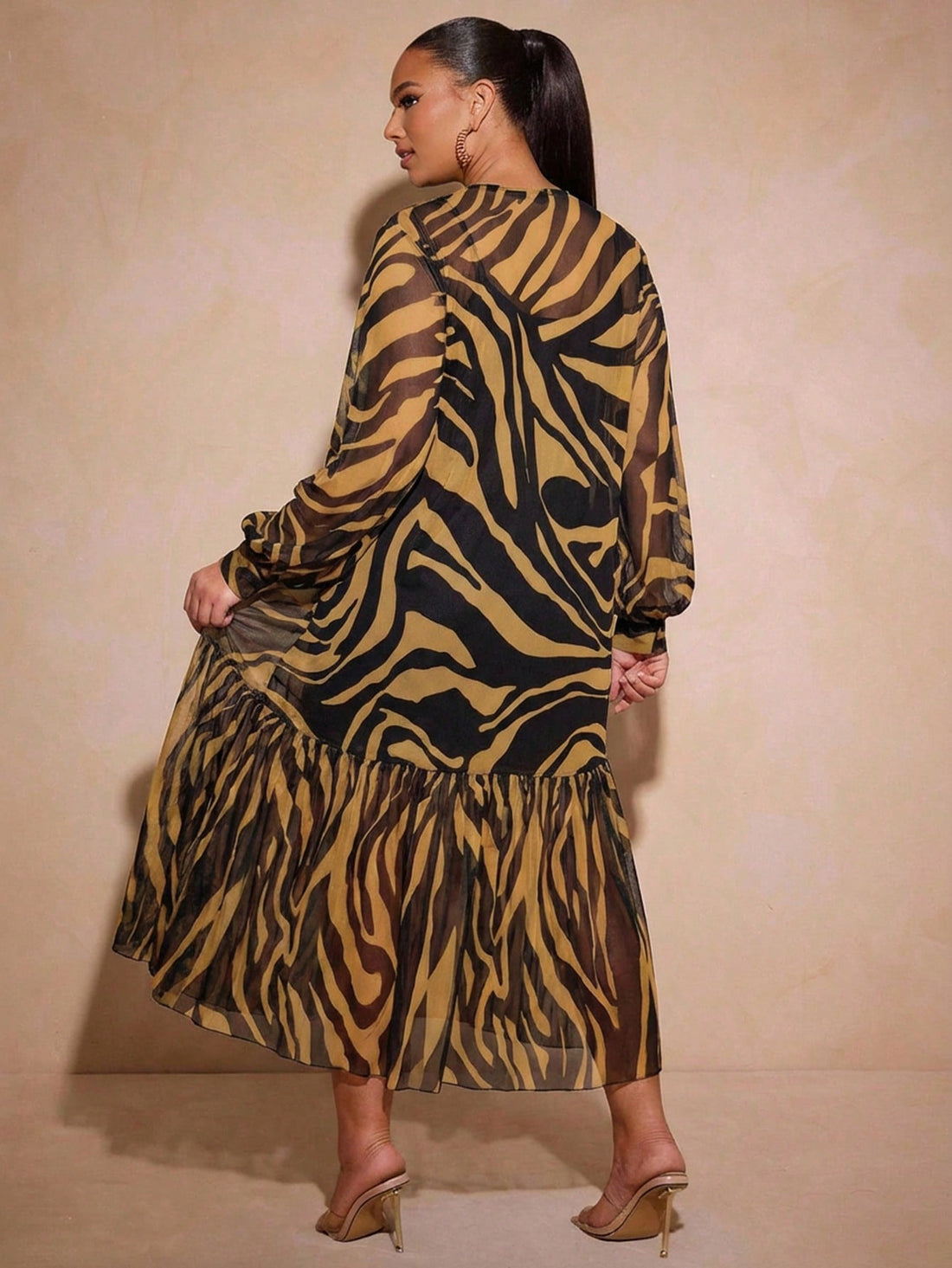 Make a bold fashion statement with this playful tunic top that blends edgy and elegant in one fabulous piece. Featuring a striking tiger print design, sheer mesh construction, and dramatic balloon sleeves, it's perfect for anyone who loves to stand out. The delicate tulle ruffle hem adds a flirty touch that keeps things fun and feminine. Layer it over a slip or cami for a chic, modern look that works for casual outings or creative styling moments. Comfort meets confidence in this show-stopping top.