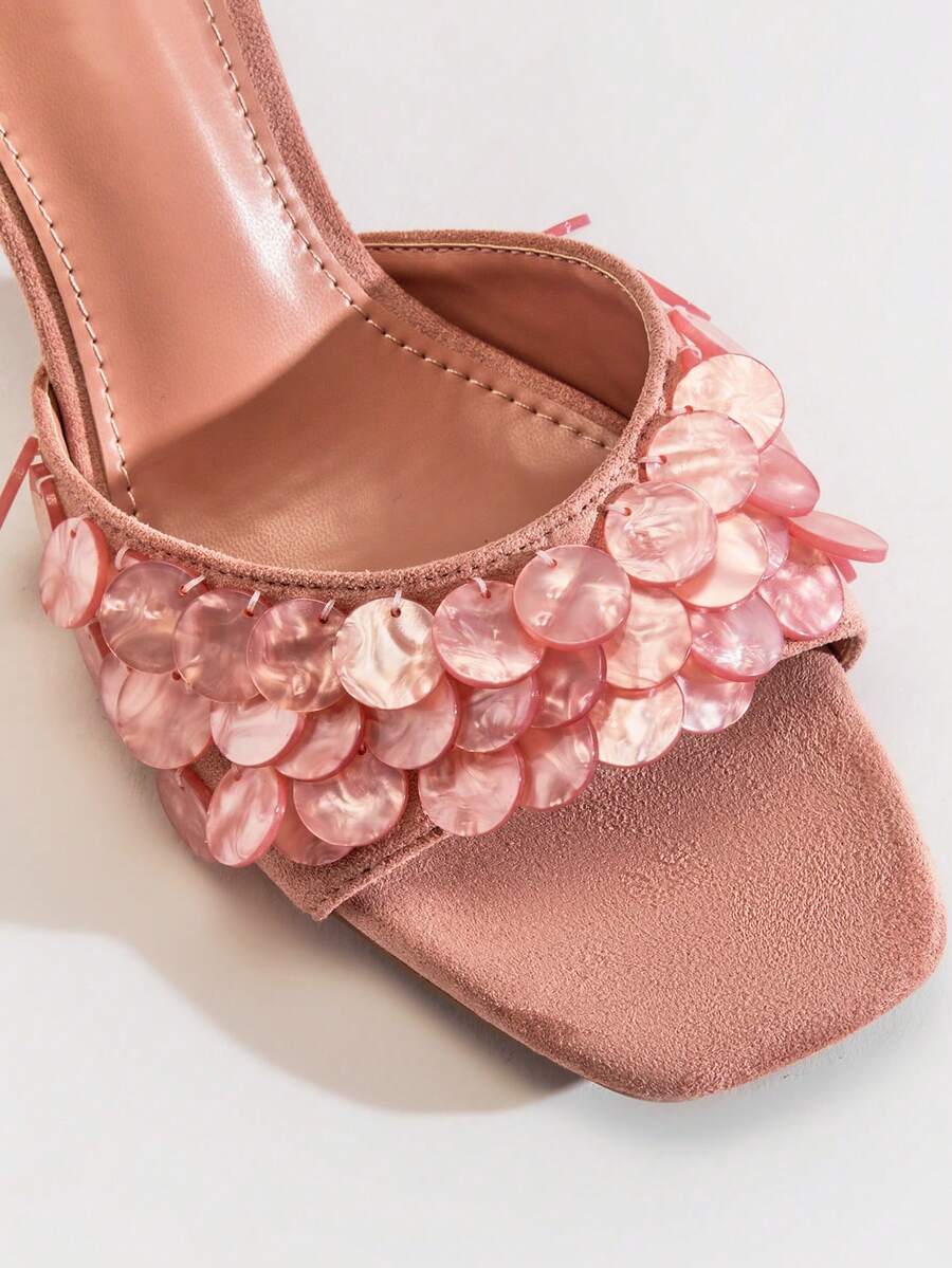 Close-up of coral pink mule sandal strap with layered pearly discs and stitched footbed