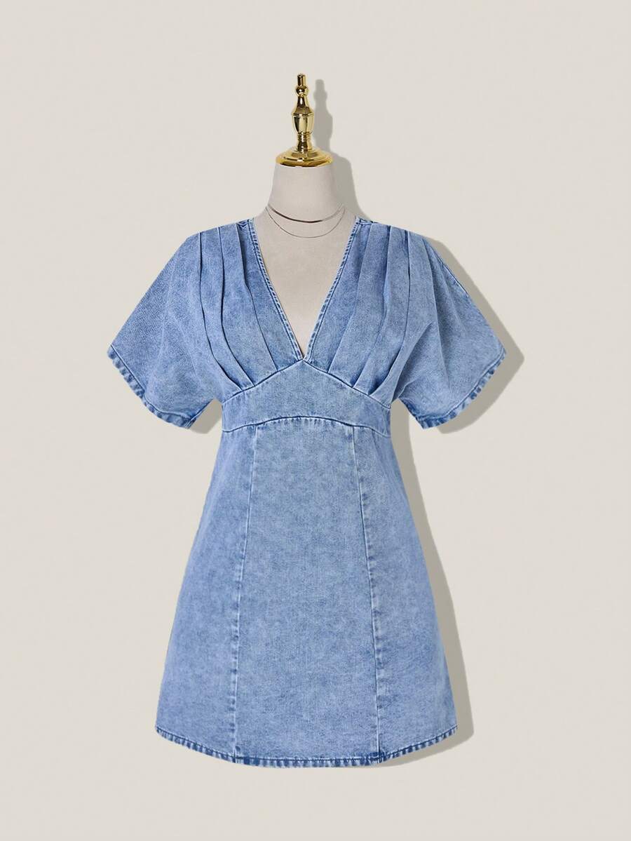 Front view of light-wash A-line denim mini dress with V neckline and curved stitched hem