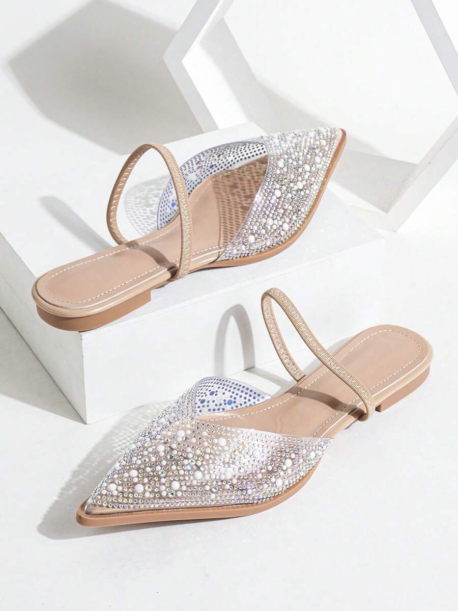 Nude pointed toe flat mule sandals with rhinestone and pearl embellished clear vamp.