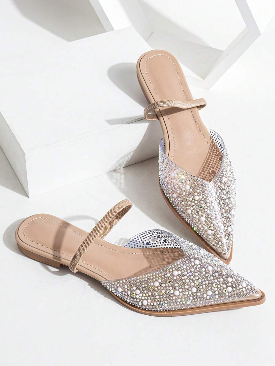 Nude pointed toe flat mule sandals with rhinestone and pearl embellished clear vamp.