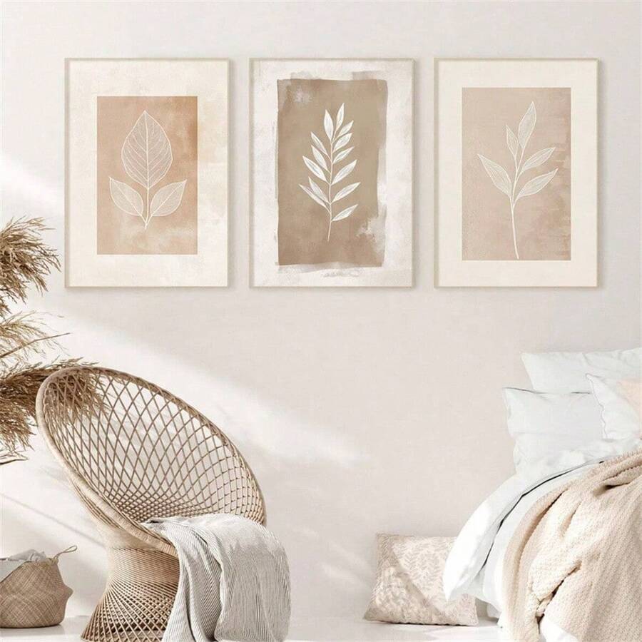 Front living room mockup of three beige botanical leaf prints in light wood-look frames above a sofa