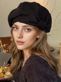 Model wearing black textured brimless beret with oversized bow for casual styling
