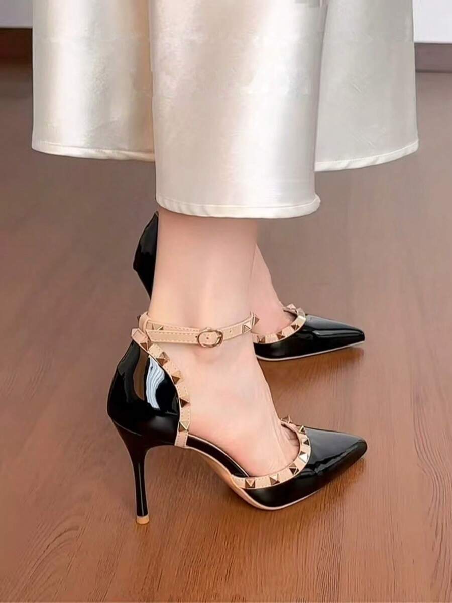 On-foot side view of black pointed-toe stiletto heels with studded beige ankle straps