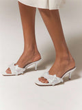 Worn front view of white embellished kitten-heel mules with clear layered vamp details