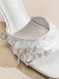 Close-up of white mule sandal strap with translucent discs and stitched square-toe footbed