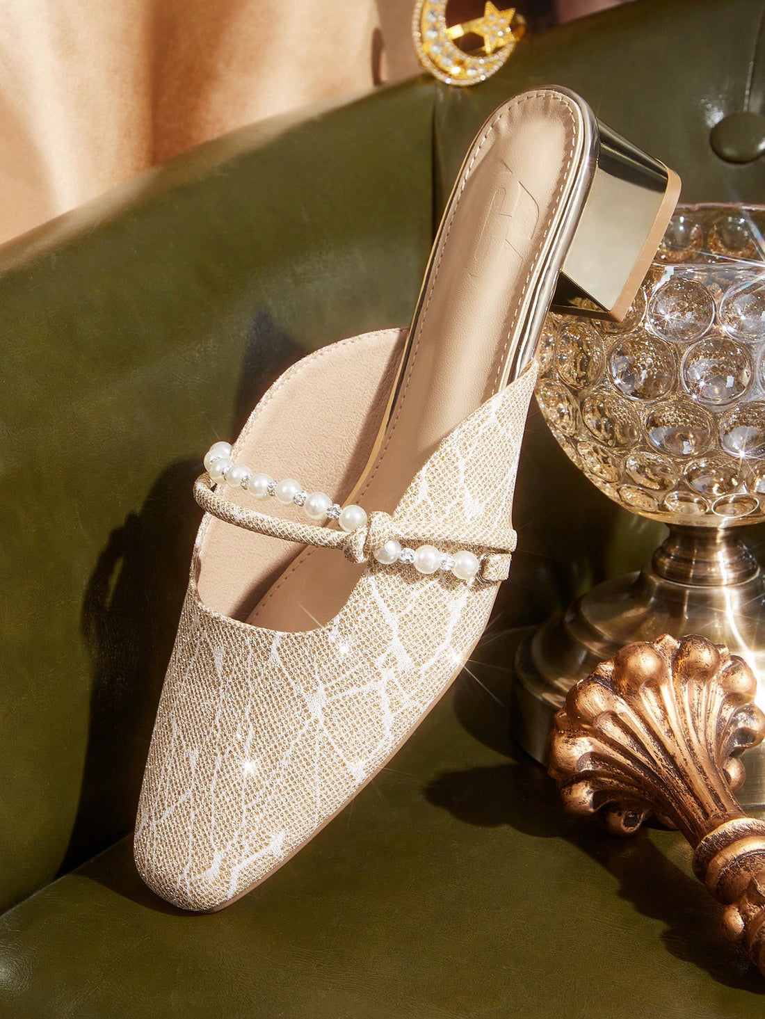 Step into sophistication with these elegant heeled sandals, designed for the discerning woman. The pointed toe silhouette elongates the foot, while the lustrous pearl strap adds refined glamour. Featuring a sturdy metallic block heel, these mules deliver all-day comfort without compromising on style. Perfect for evening events, cocktail parties, and upscale occasions, they transition seamlessly from day to night. The metallic finish catches light beautifully, making them a versatile addition to any formal w