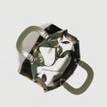 Overhead view into open camouflage handbag showing pale interior, zipper and twin olive handles