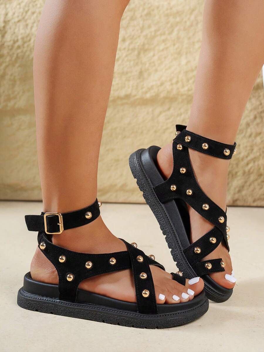 Side view of black gold-studded ankle-strap sandals with buckle closure