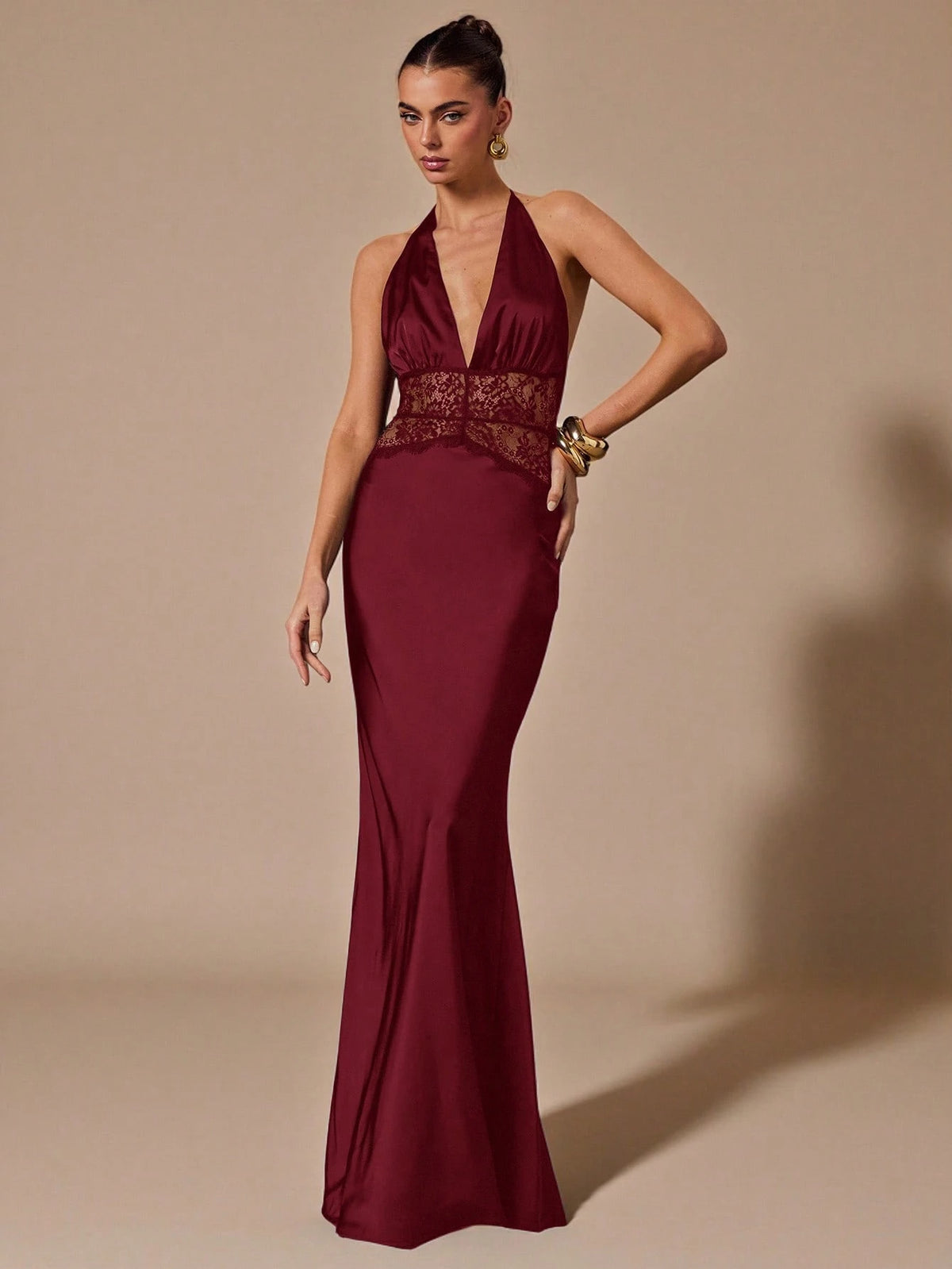 Woman wearing a burgundy evening gown with lace detailing on a beige background