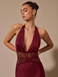 Woman wearing a burgundy halter neck dress with lace detail on a beige background