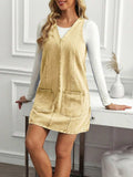Front three-quarter view of sand khaki A-line denim mini dress layered over a white top