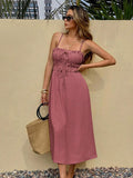Pink tie-front midi sundress with straw tote on pebble ground