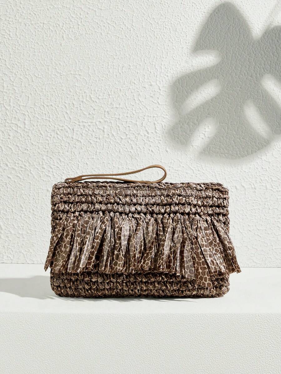 Brown woven clutch bag with animal print fringe tassels zipper top and wristlet strap against white textured wall