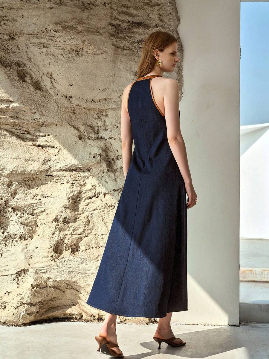 Rear three-quarter view of dark indigo sleeveless denim maxi dress with flared A-line skirt