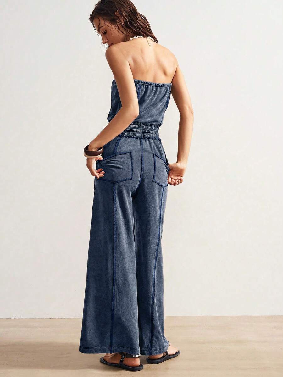 Back view of washed blue strapless jumpsuit with rear patch pockets and wide straight legs