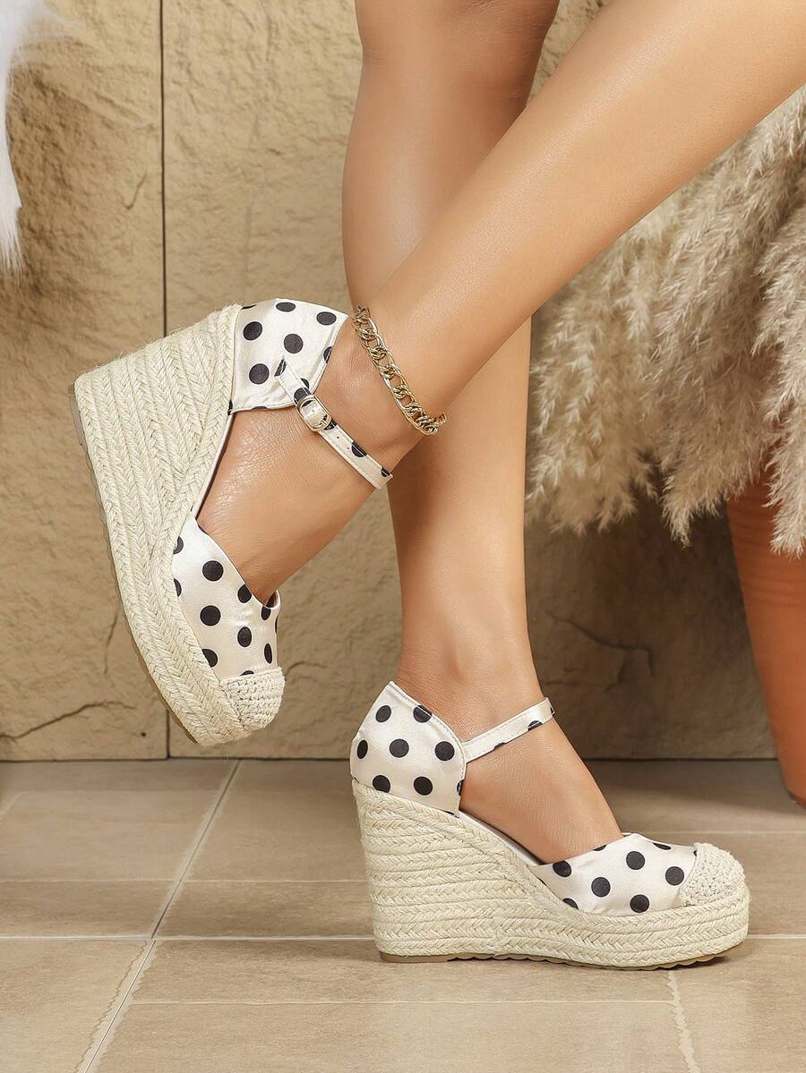 Side view of polka-dot closed-toe espadrille wedge sandals worn indoors with ankle buckle straps