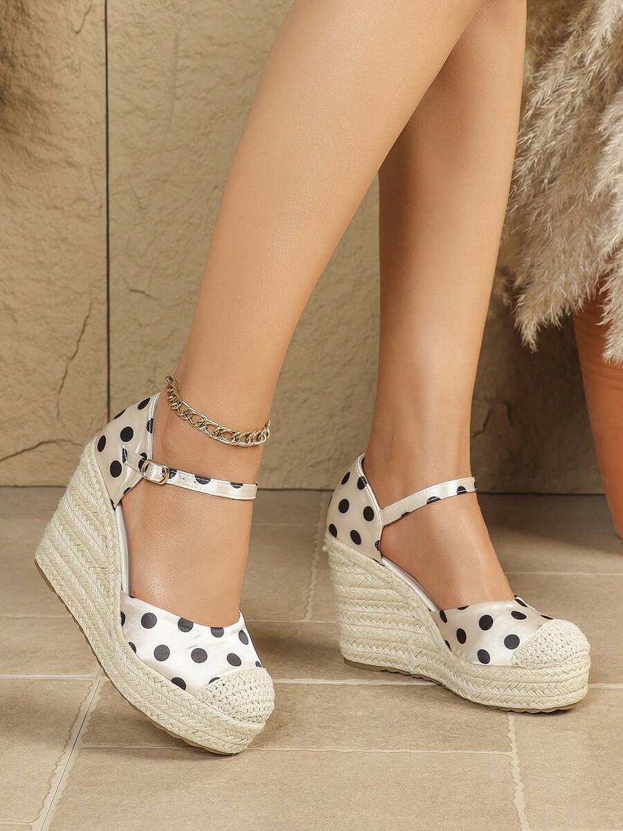 Front-side view of polka-dot closed-toe espadrille wedges with braided rope platforms