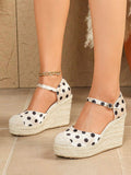 Front three-quarter view of ivory polka-dot espadrille wedge sandals with ankle straps