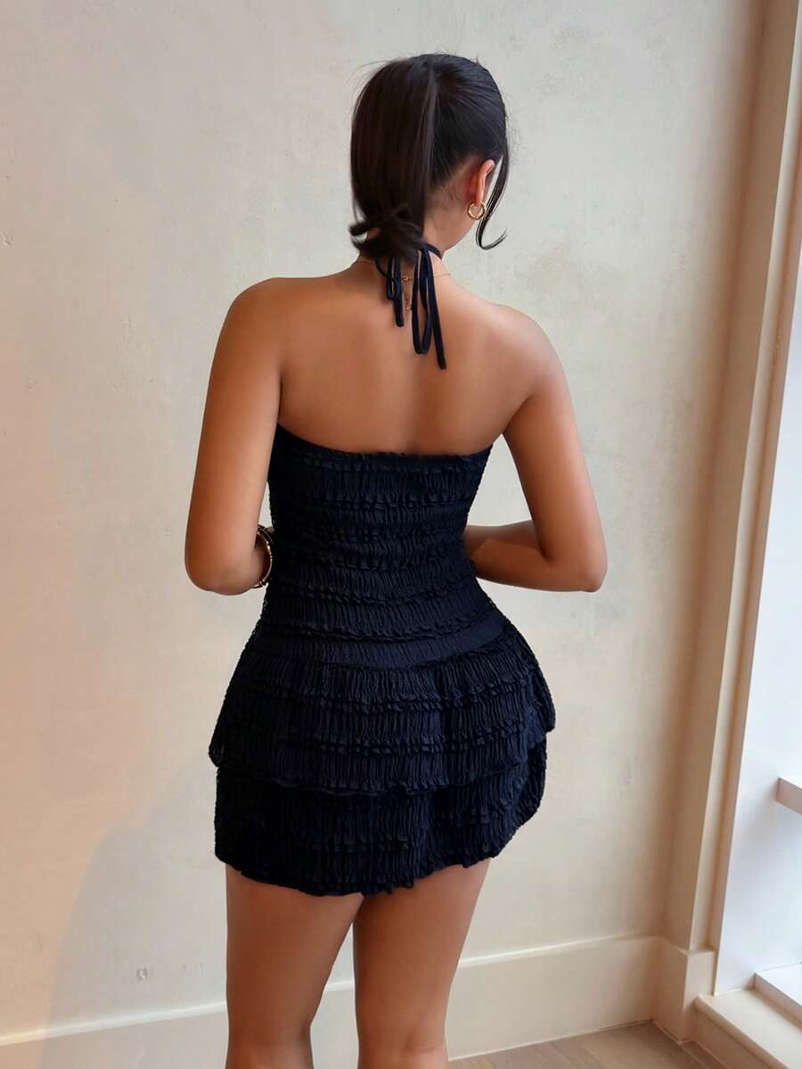 Back view of dark halter mini dress with open back and flouncy tiered hem