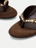 Close-up of brown thong sandal straps with champagne-tone studs and rounded-square footbeds