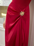 Close-up of ruby red dress showing gathered satin-look skirt and gold floral hip ornament