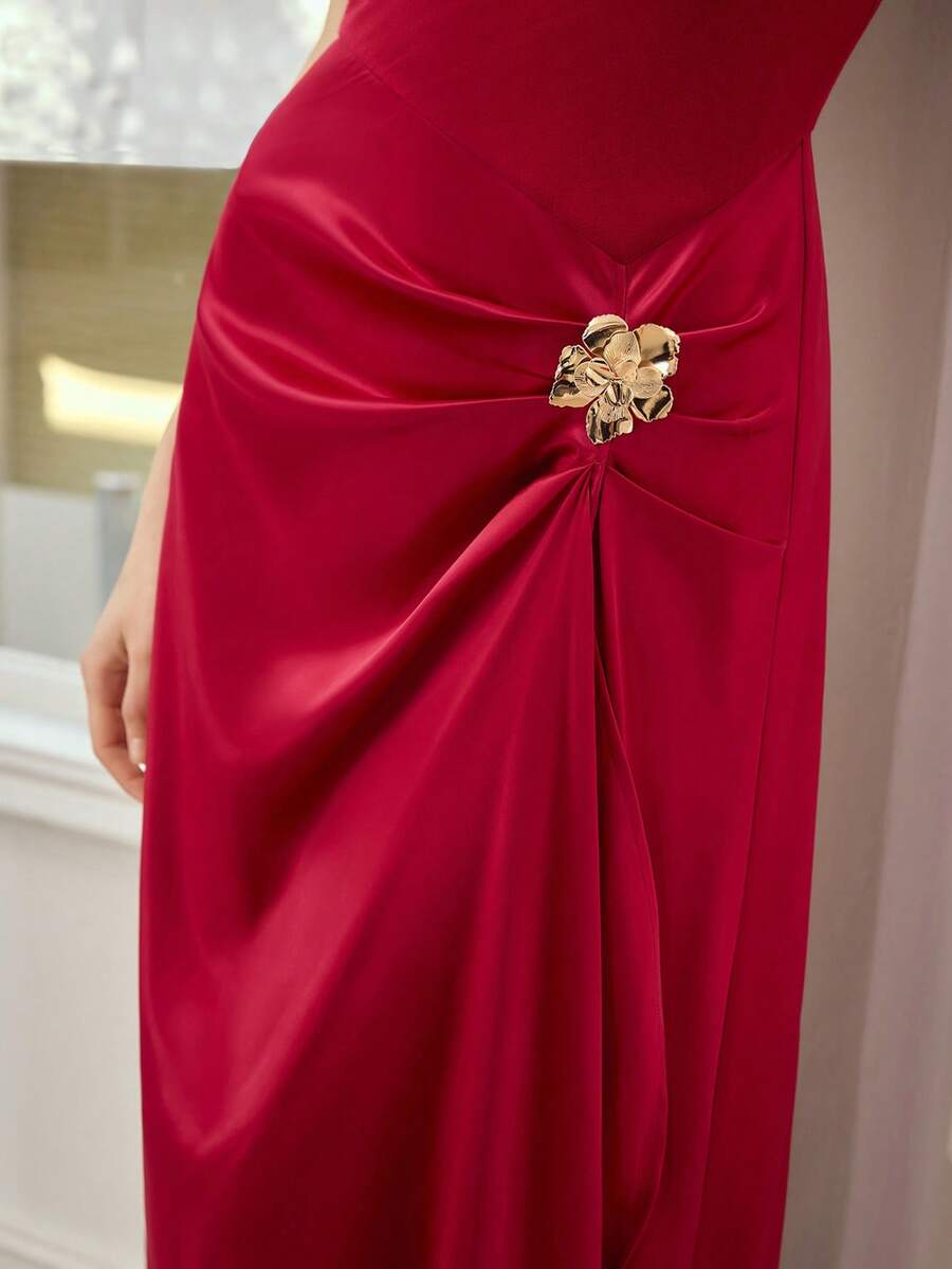 Close-up of ruby red dress showing gathered satin-look skirt and gold floral hip ornament