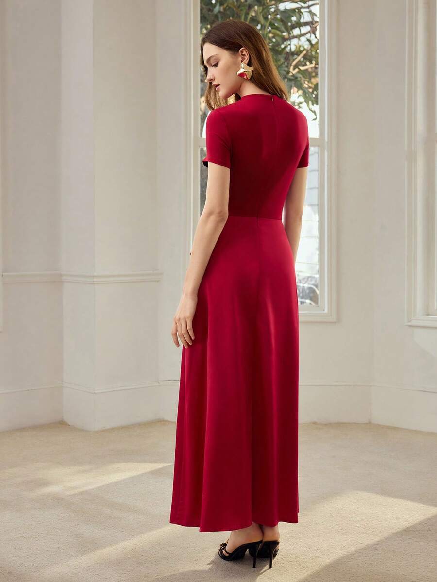 Full front view of ruby red draped maxi dress with short sleeves, gold floral hip detail, and slit