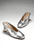 Silver three-quarter top view of patent mule pumps with closed vamp, open back, softly squared toe, and flared block heel