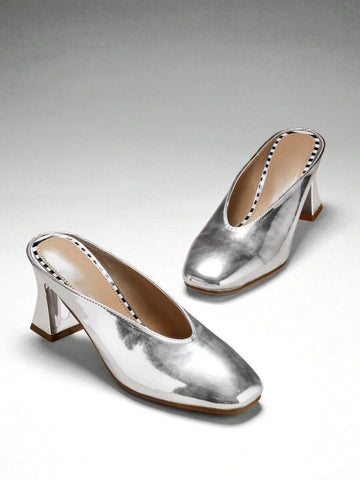 Silver three-quarter top view of patent mule pumps with closed vamp, open back, softly squared toe, and flared block heel