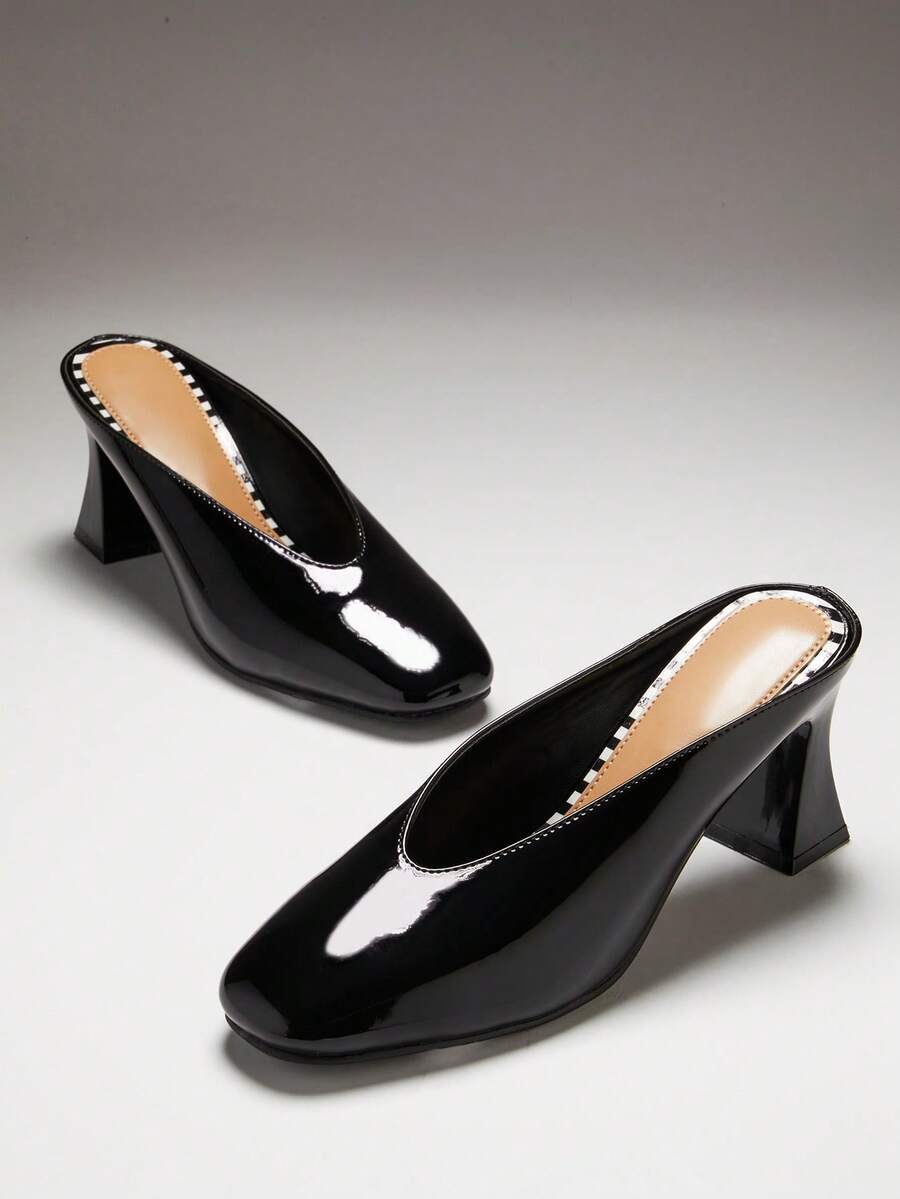 Black three-quarter top view of patent mule pumps with closed vamp, open back, softly squared toe, and flared block heel