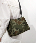 Green camouflage handbag worn at the hip with dark shoulder strap over a white outfit