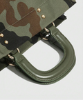 Close-up of olive handbag handle stitching, gold-tone rings and rivets on green camouflage fabric