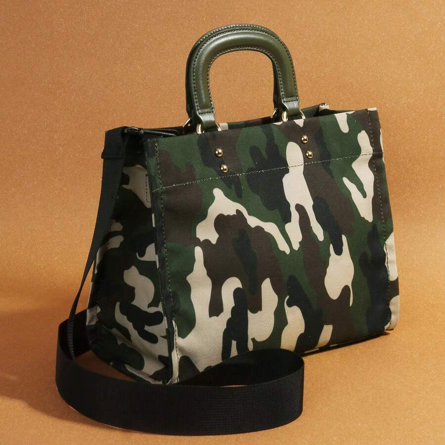 Three-quarter view of green and cream camouflage handbag showing gusseted side and black shoulder strap